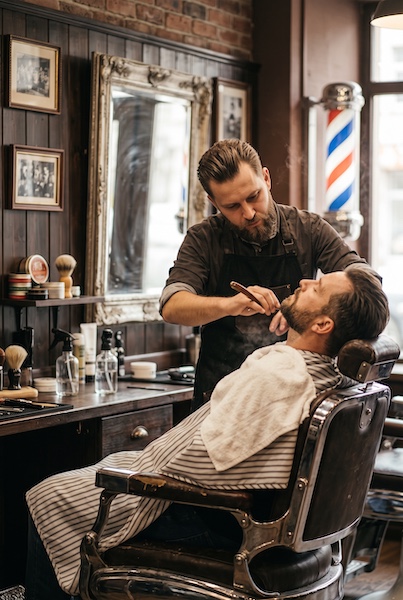Barbearia tradicional | Barba na navalha com toalha quente Barbeiro fazendo a barba de um cliente com navalha em uma barbearia tradicional masculina